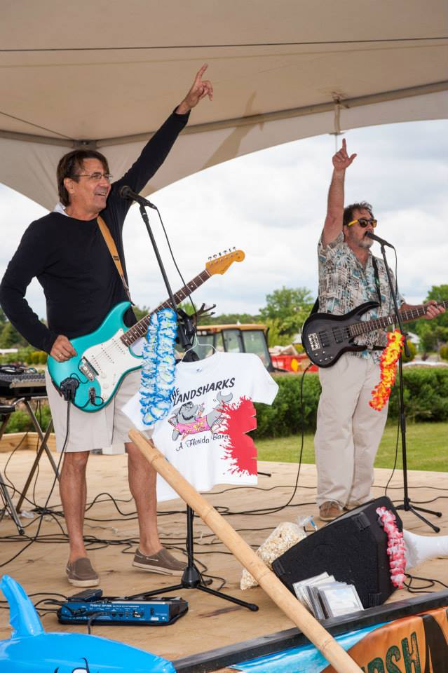 Two men are playing guitars and singing into microphones on a stage.
