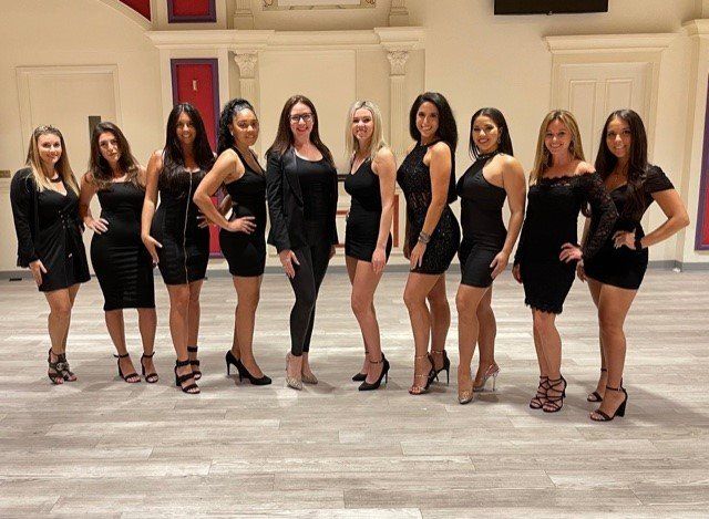 A group of women in black dresses are posing for a picture.