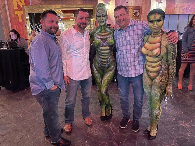 A group of men are posing for a picture with a woman in a body painted costume.