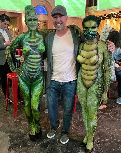 A man and two women are standing next to each other with their bodies painted green.