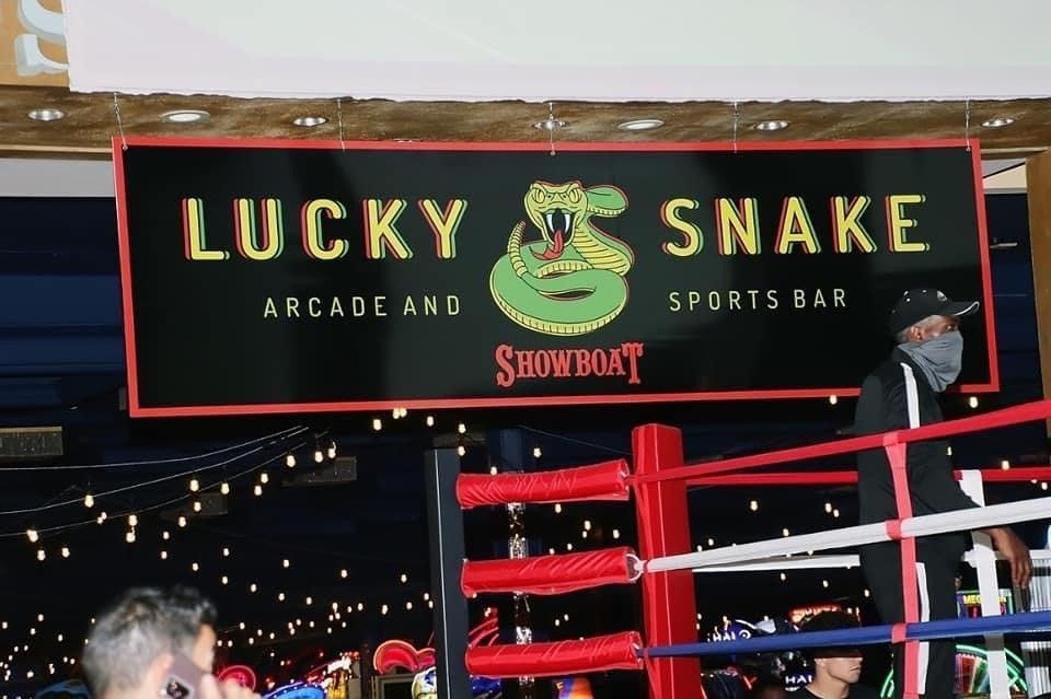 A sign for lucky snake arcade and sports bar hangs above a boxing ring