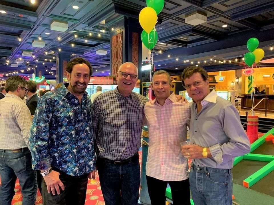 A group of men are posing for a picture in a room with balloons.
