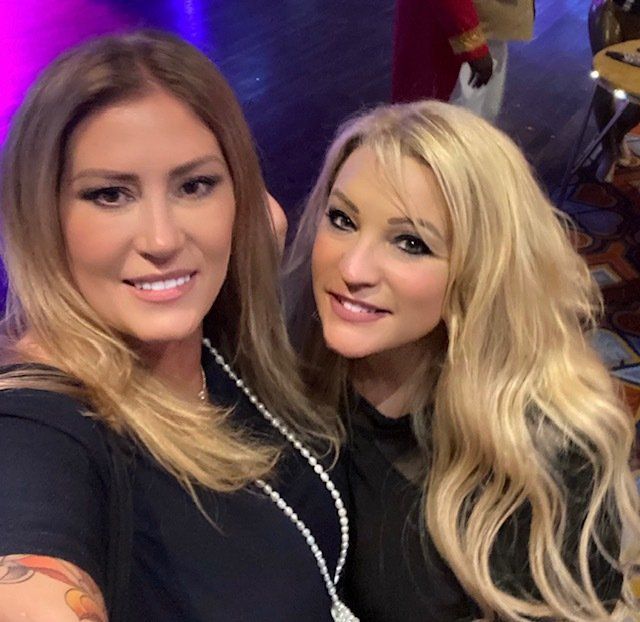 Two women are posing for a picture and one has a tattoo on her arm