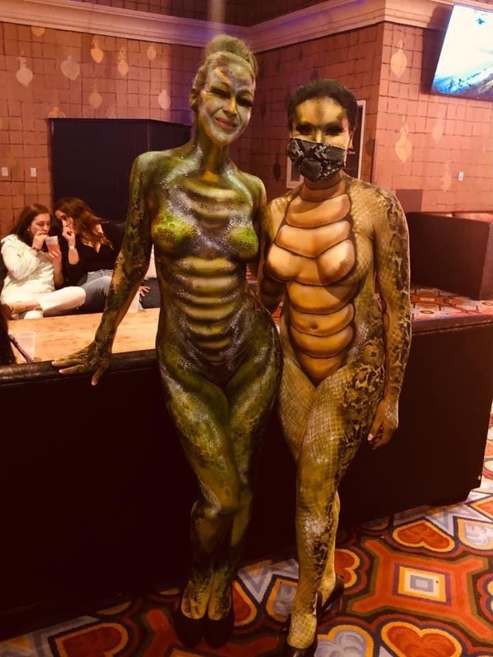 Two women are standing next to each other in a room with their bodies painted.