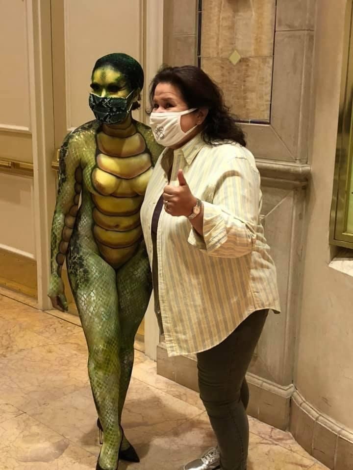 A woman wearing a mask is standing next to a woman dressed as a lizard.