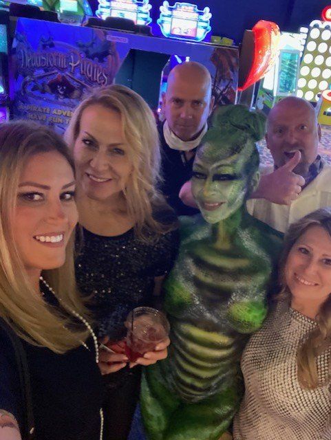 A group of people are posing for a picture with a statue of a woman with body paint.