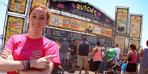 A woman in a pink shirt is standing in front of a butch 's sign