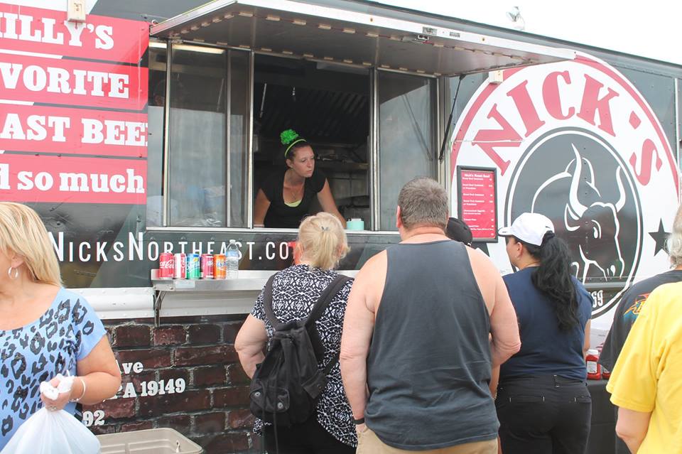 A group of people standing in front of a nick 's food truck