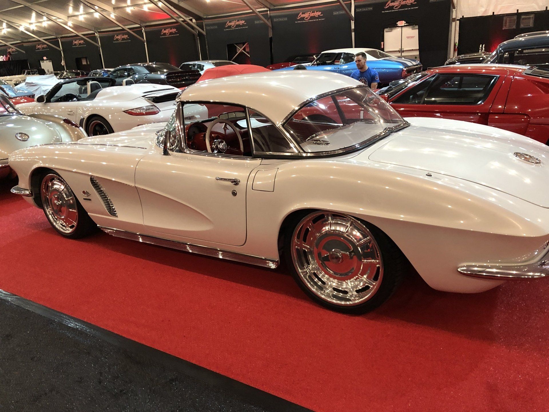 a white corvette parked on a red carpet at a car show