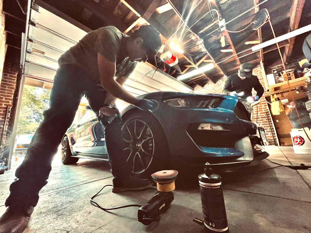 a man is polishing a car in a garage .