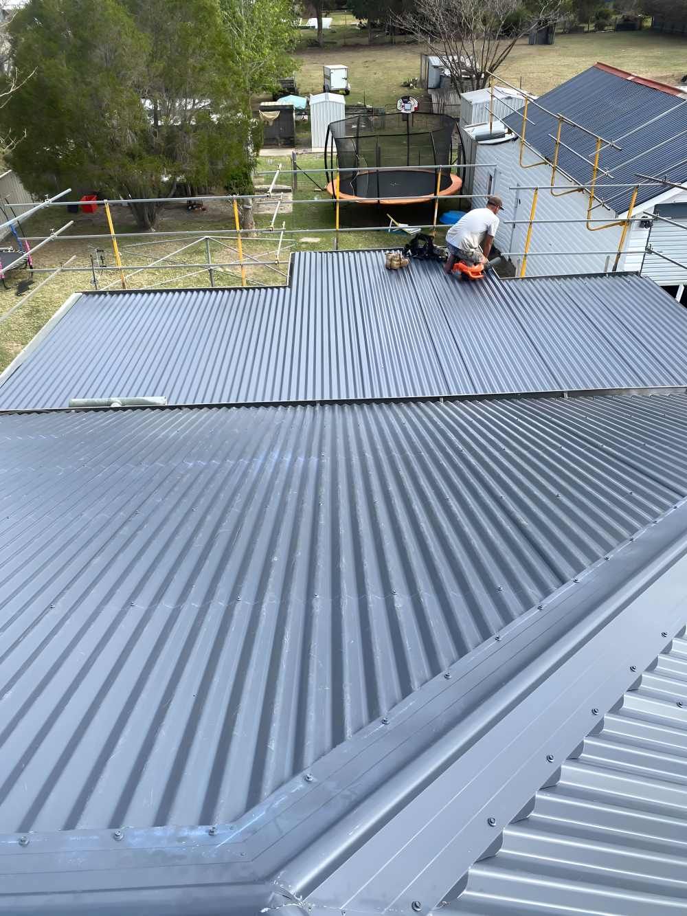A Man Is Repairing The Roof — Southern Cross Roof Plumbing in Murwillumbah, NSW