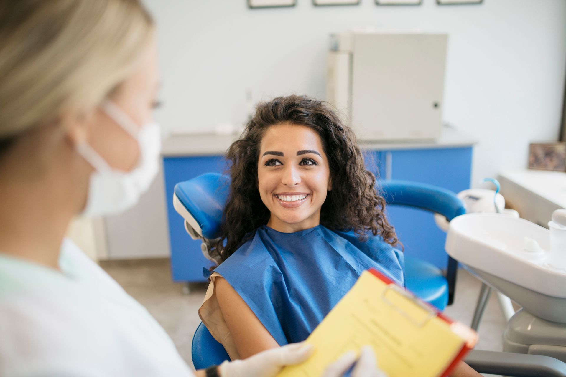 A woman is sitting in a dental chair talking to a dentist.