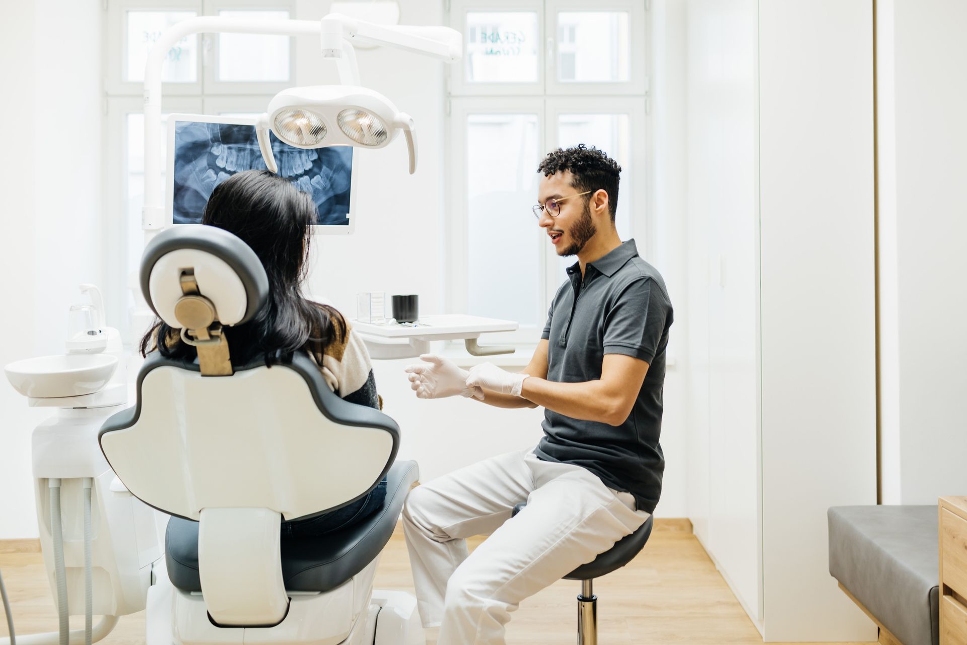 A dentist is talking to a patient in a dental chair.