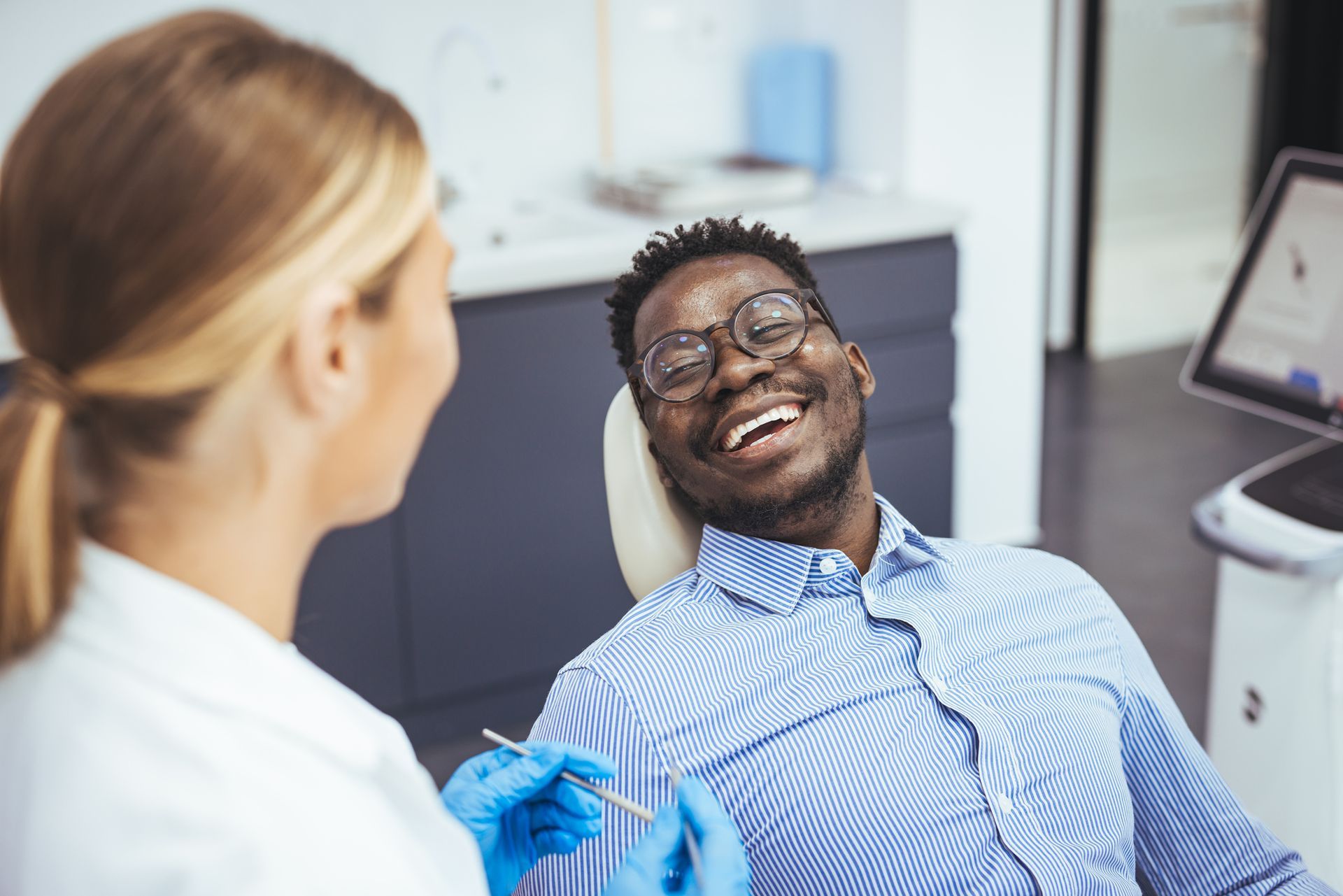 A man is smiling while sitting in a dental chair.
