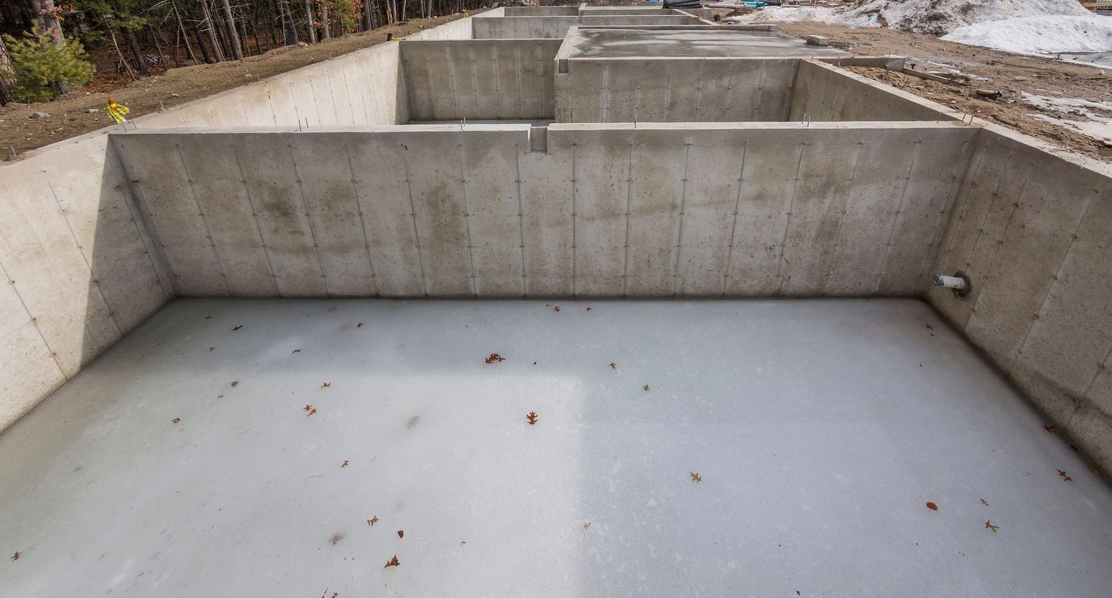 A large concrete pool is being built in the middle of a forest.
