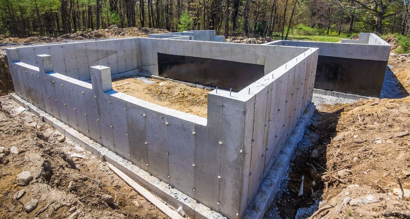 A concrete foundation for a house is being built in the dirt.