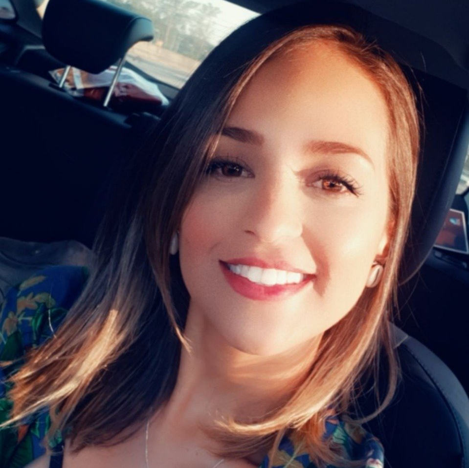 Uma mulher sorri sentada no banco de trás de um carro.