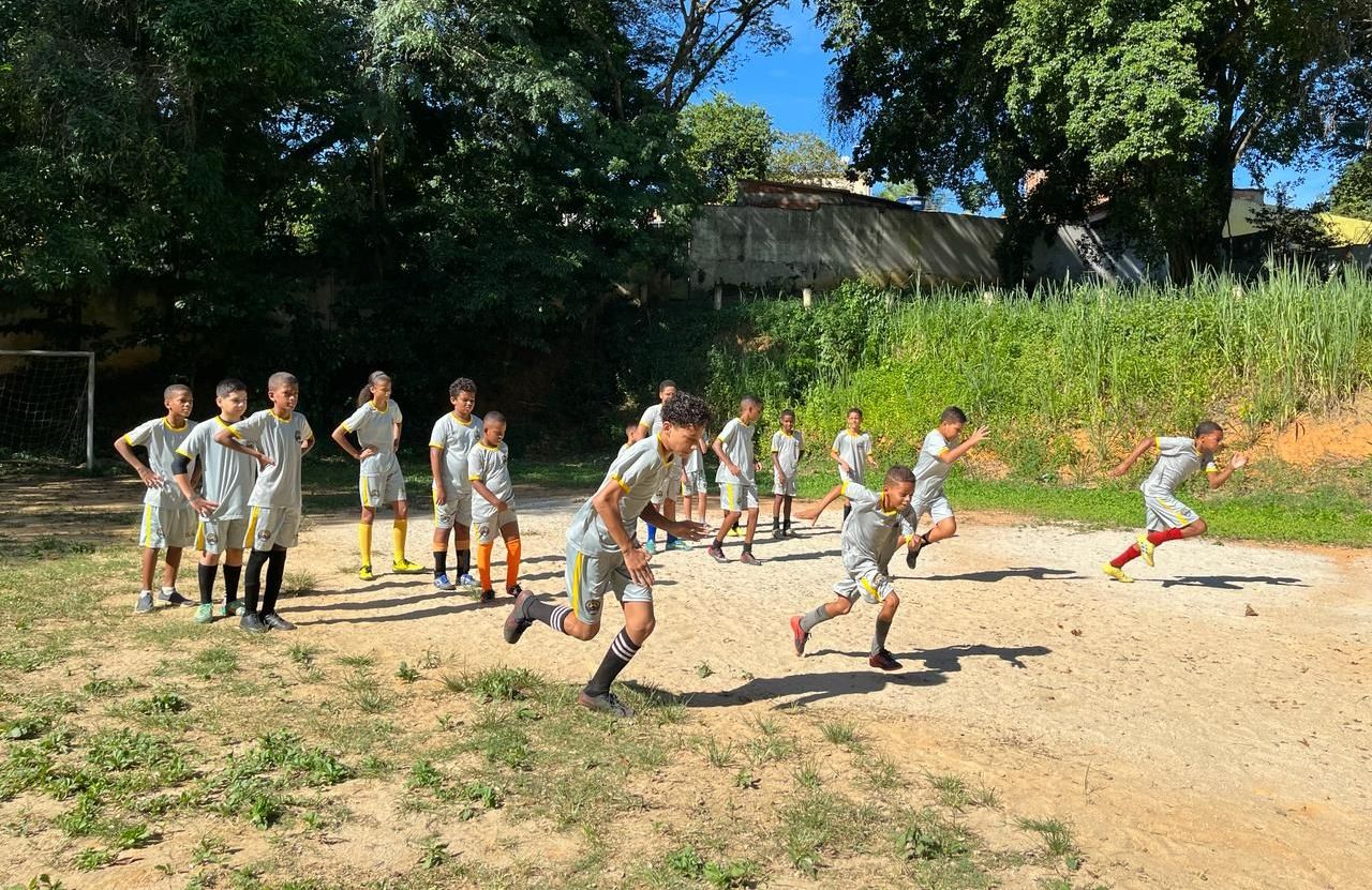 Um grupo de crianças está jogando futebol em um campo de terra.