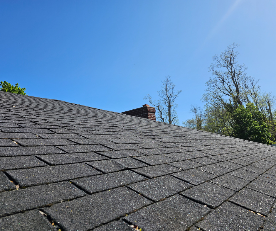 A close up of a roof with a chimney and trees in the background.