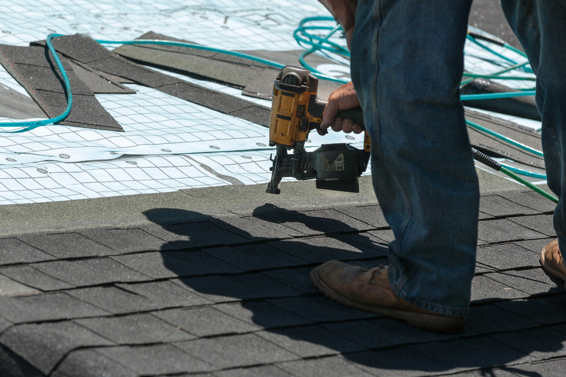 A man is working on a metal roof with a drill.