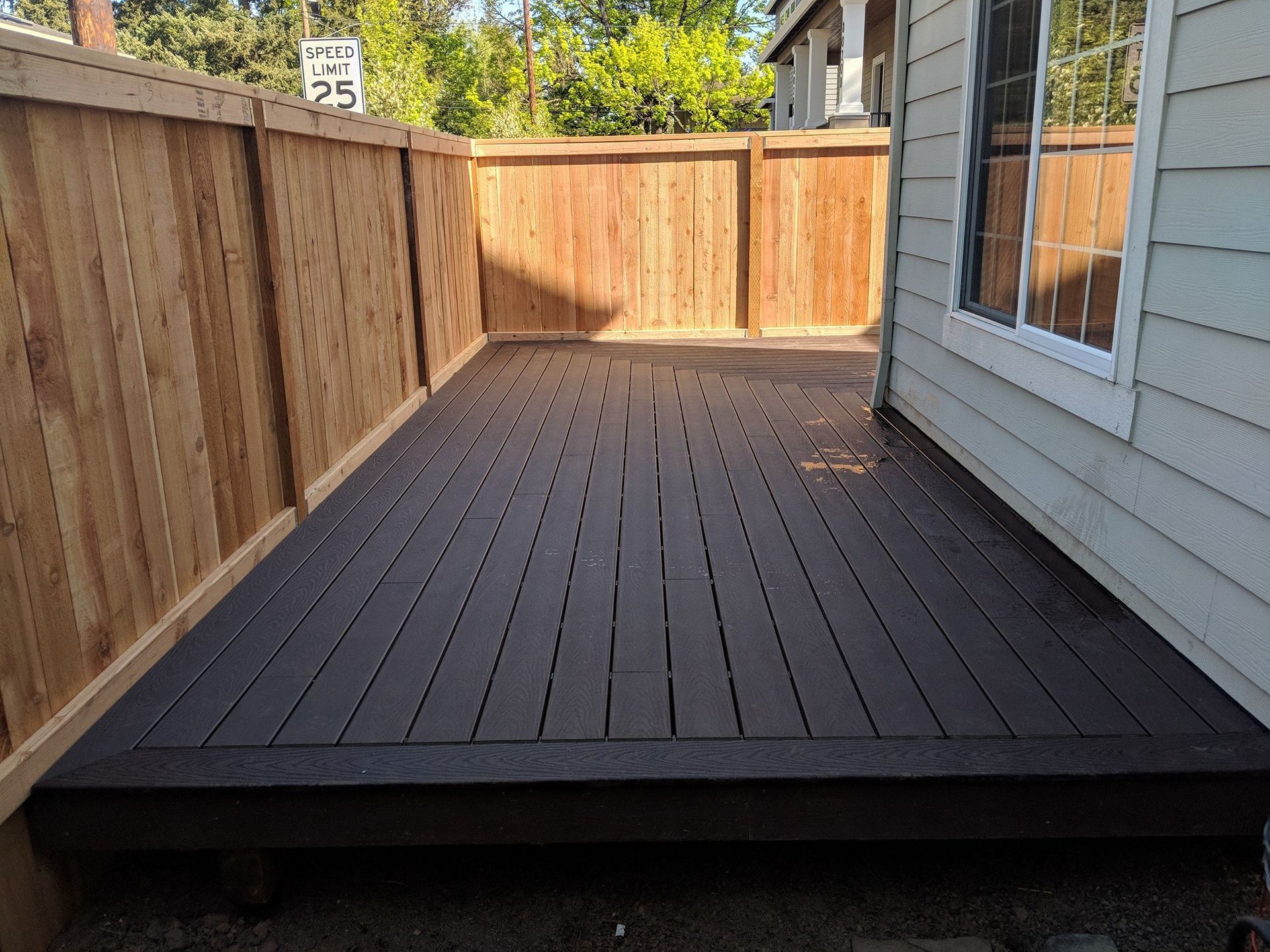Dark deck enclosed by wooden fence and siding. Speed limit sign visible.