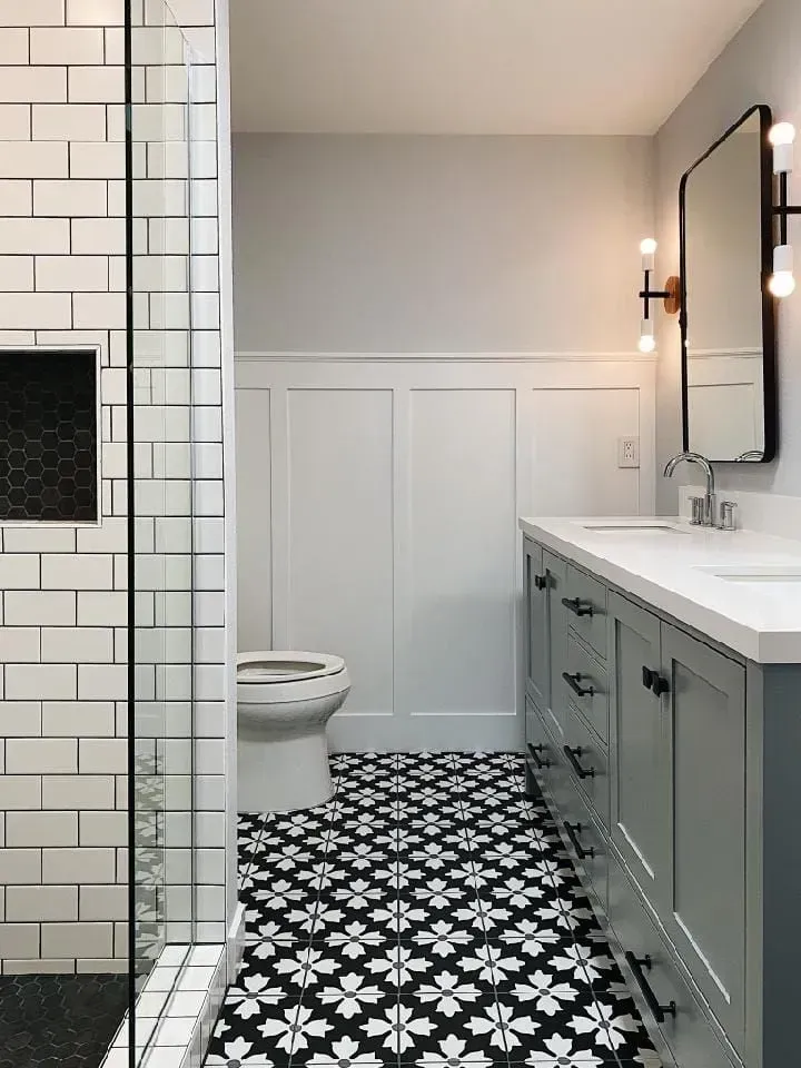 Bathroom with white subway tile shower, patterned floor, and gray vanity with mirror.