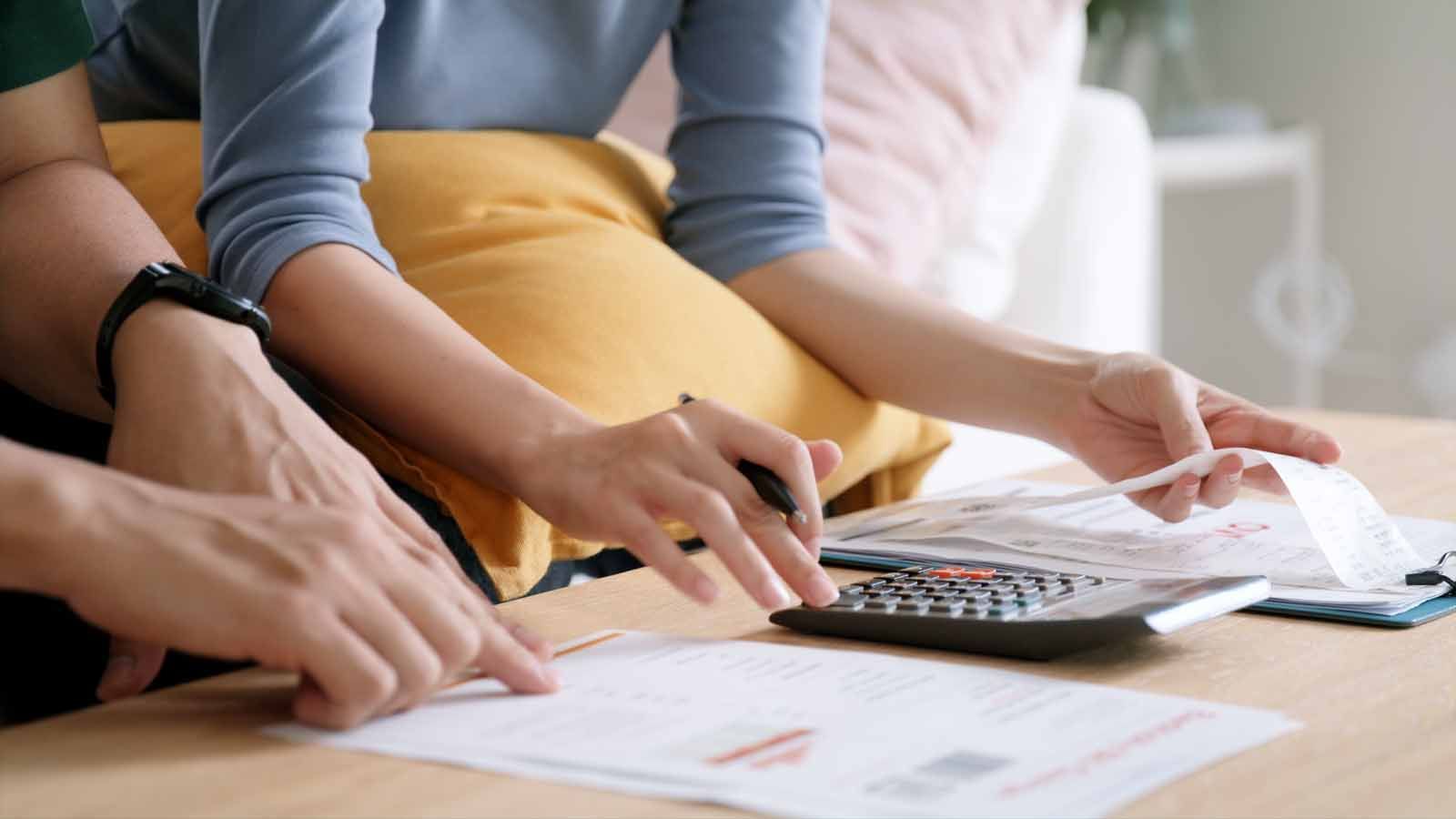 A man and a woman are sitting at a table using a calculator.