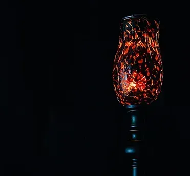 A wine glass with a candle inside of it on a black background.