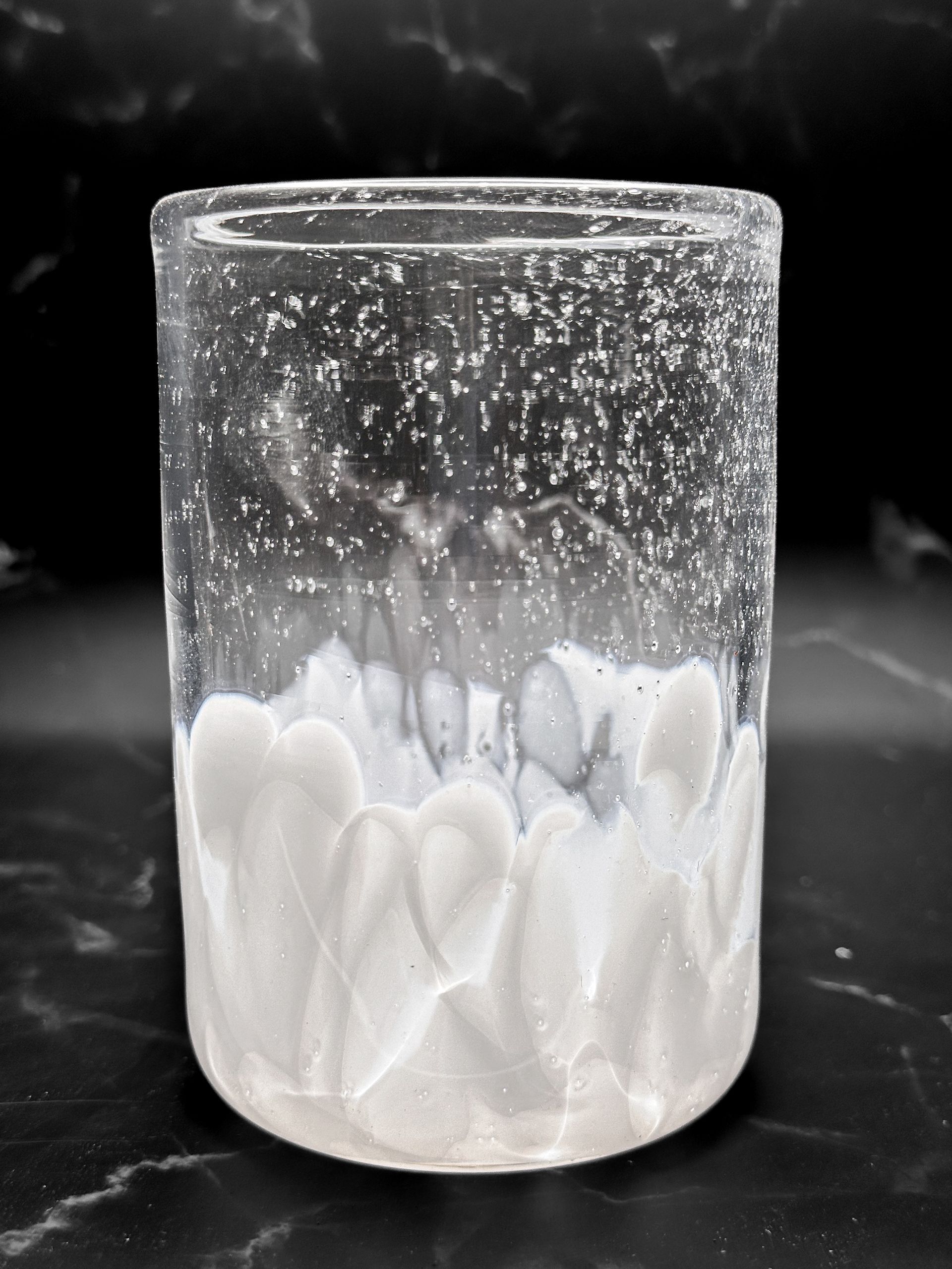 A clear glass filled with white liquid on a black surface