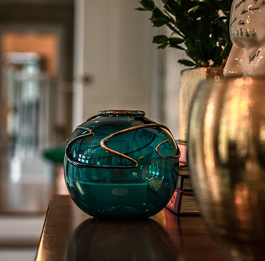 A blue vase is sitting on a table next to a plant.