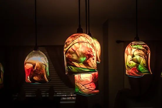 A group of colorful pendant lights hanging from the ceiling in a dark room.
