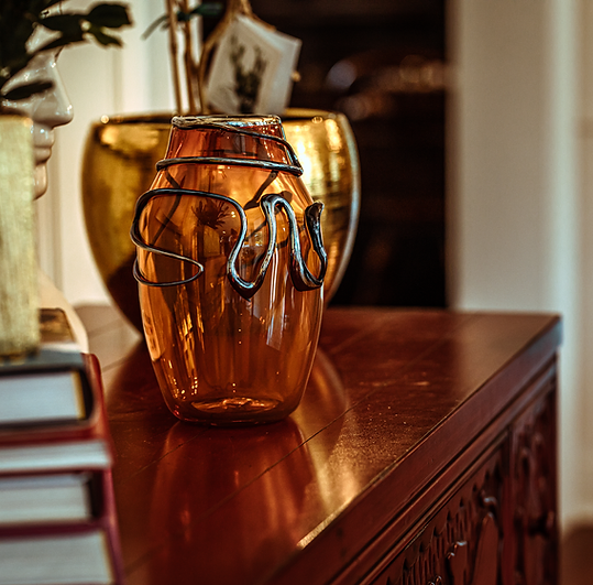 A vase sitting on top of a wooden table next to a stack of books