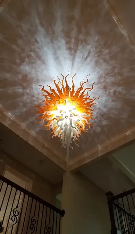 A chandelier is hanging from the ceiling of a room next to a staircase.