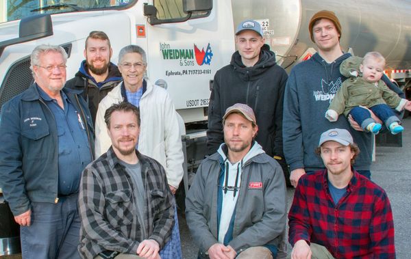 A group of men are posing for a picture in front of a truck.