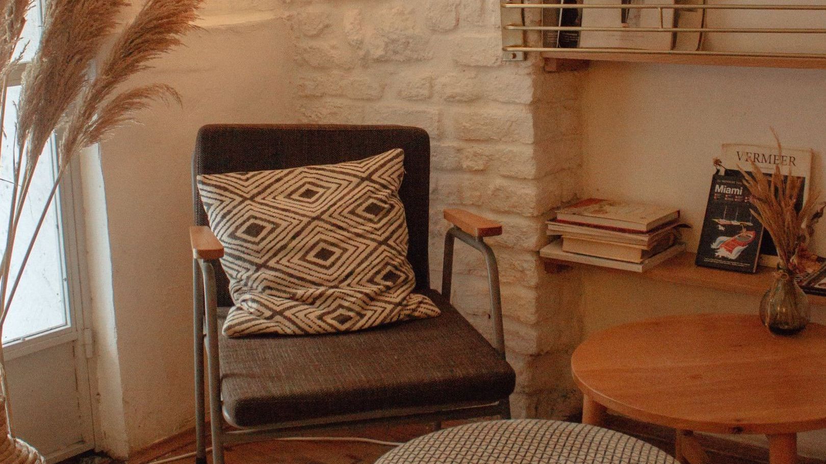 A chair with a pillow on it is sitting in a room next to a table.