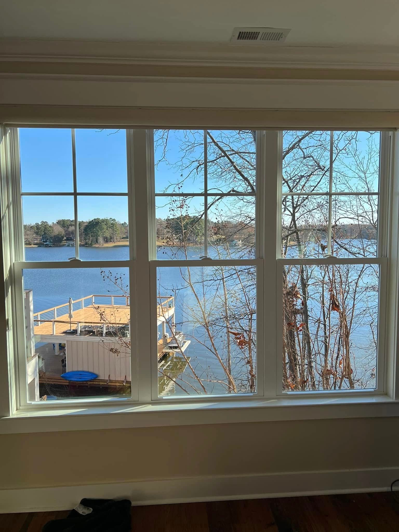 Six-pane window with view of a lake and a houseboat on a sunny day.
