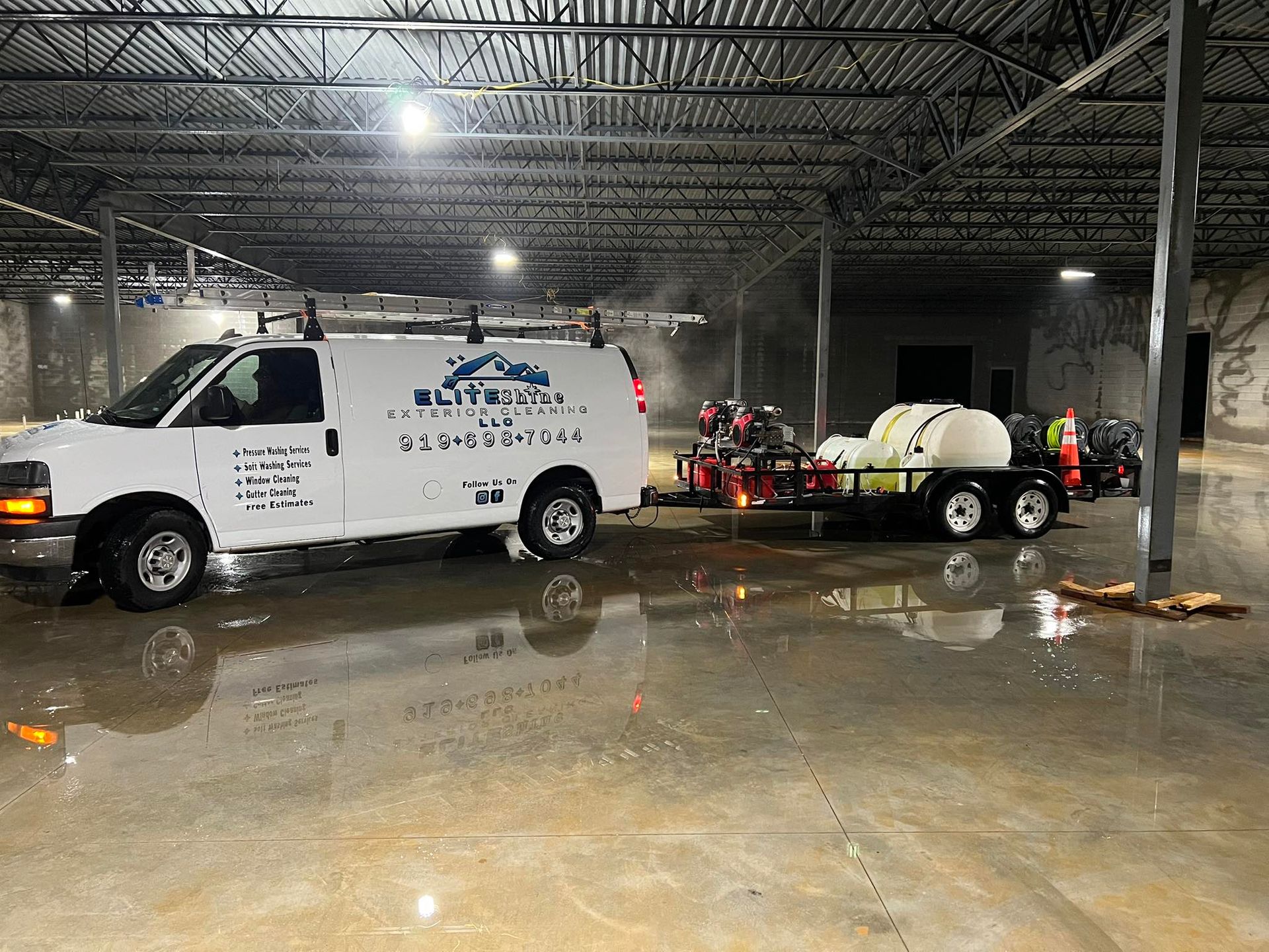 White van with trailer inside a large, empty building, potentially cleaning, wet floor.