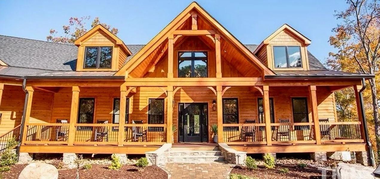 Wooden cabin with a porch and two dormer windows under a clear blue sky.