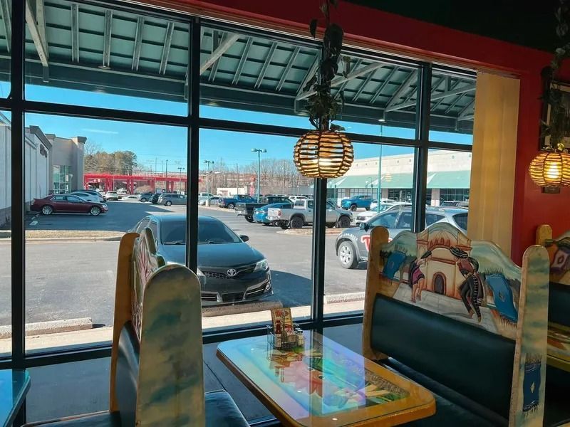 Interior of a Mexican restaurant with booths, a table, and a large window overlooking a parking lot.