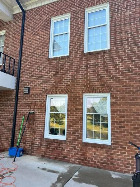 Red brick building with white framed windows. A gutter and cleaning equipment are on the side.