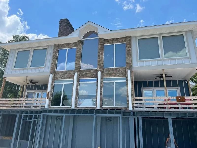 Two-story house with stone and white siding, large windows, and a partially enclosed lower level.
