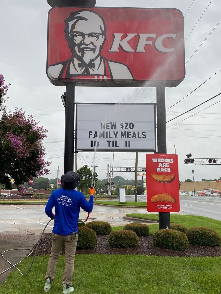A worker power washes a KFC sign with a new $20 family meals promotion.
