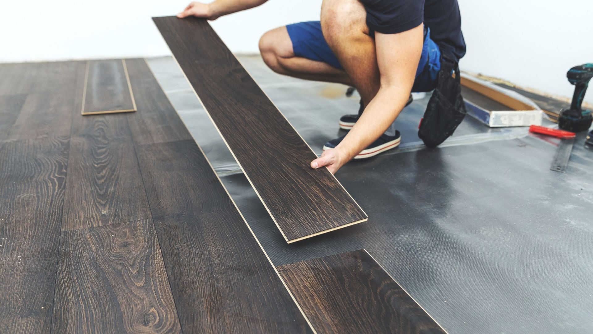 A man is installing a wooden floor in a room.