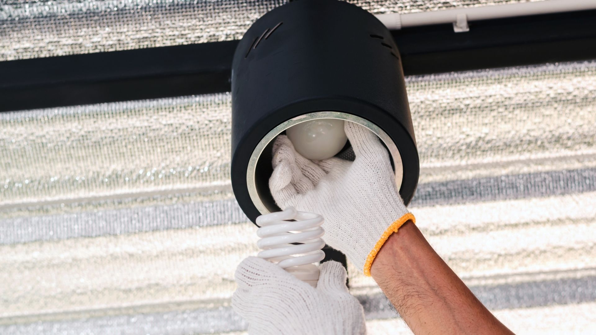 A person is changing a light bulb in a ceiling light.