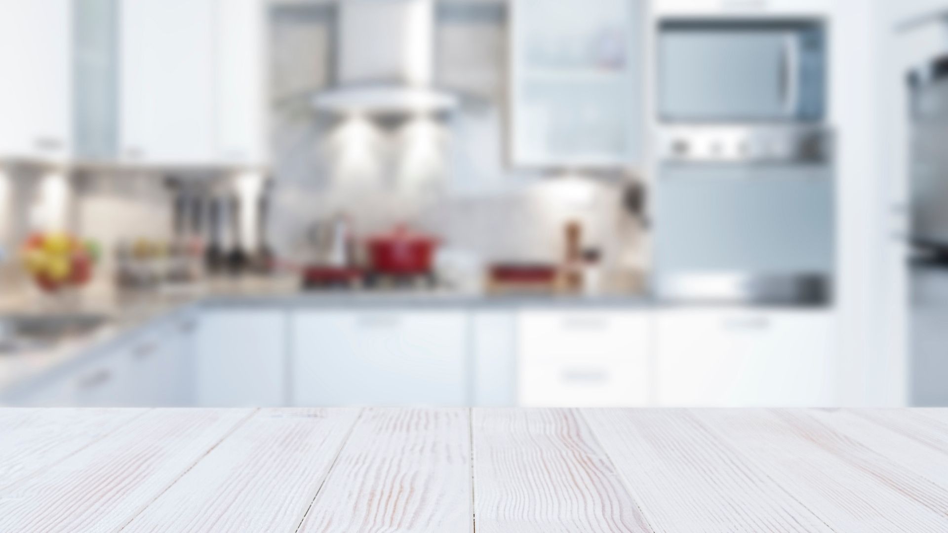 A blurred image of a kitchen with a white wooden table in the foreground.