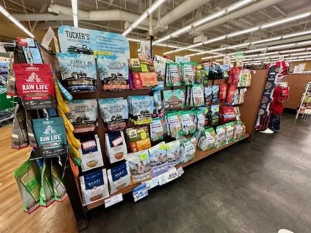 Pet food display in a store with various bags of food and marketing materials.