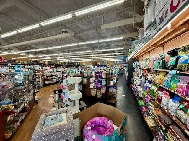 Inside a pet store, with aisles of products, pet beds, and food bags on shelves.