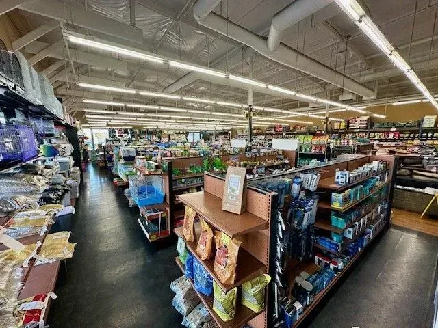 Interior view of a pet supply store with shelves of products and a dark floor.