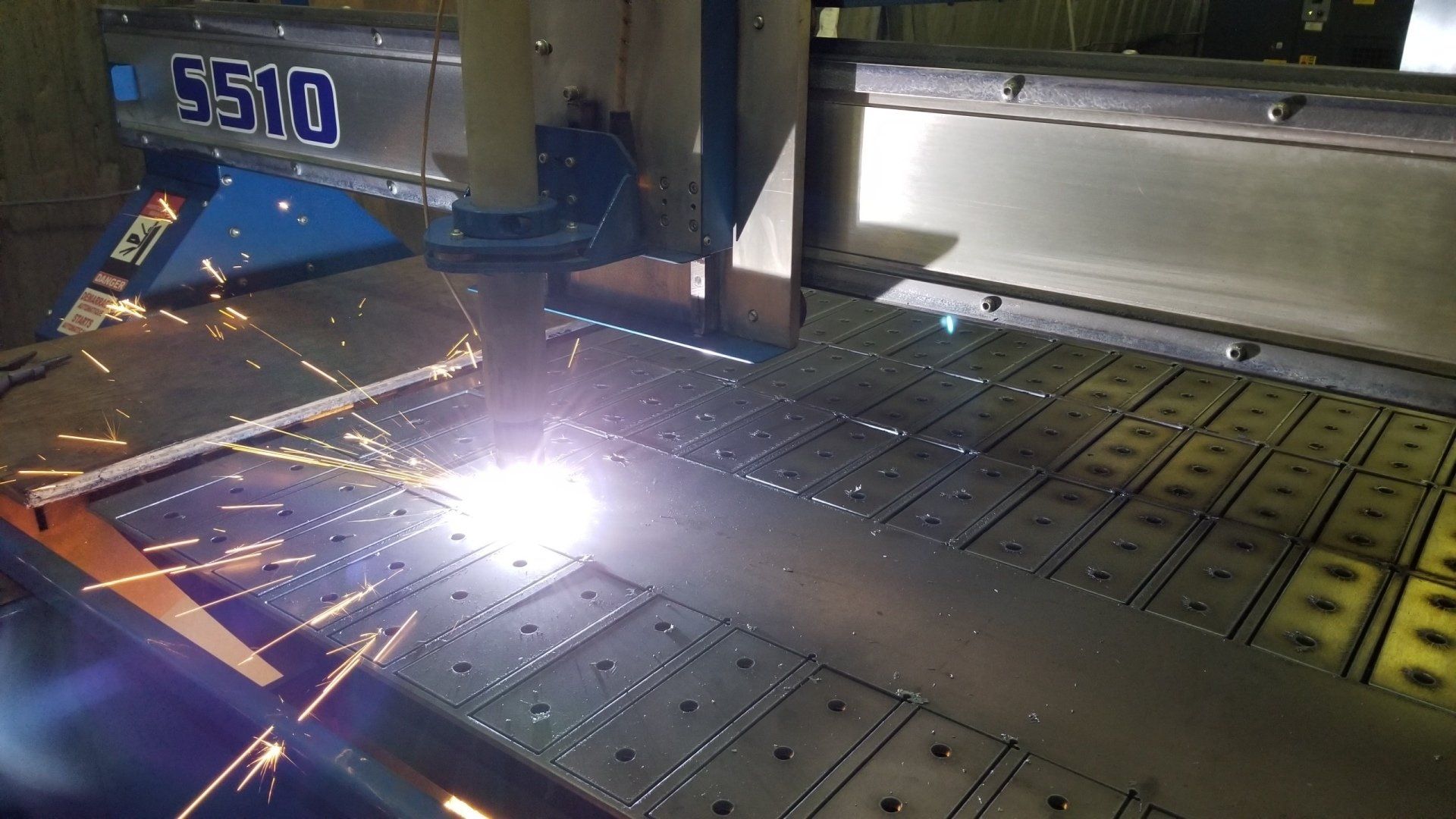 A machine is cutting a piece of metal in a factory.