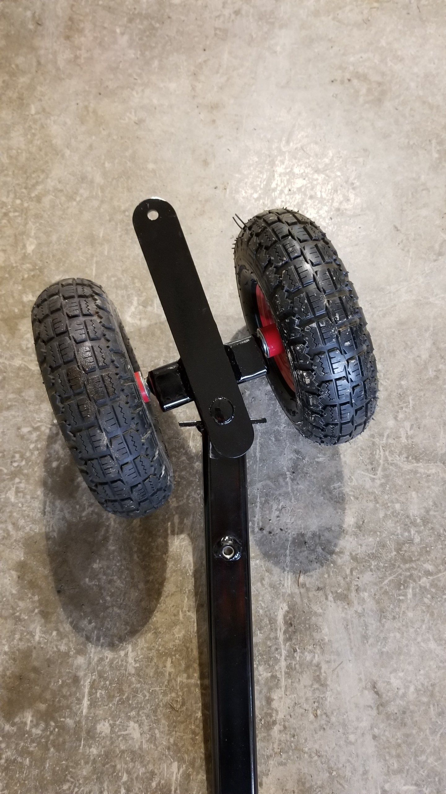 A pair of wheels sitting on top of a metal pole on a concrete floor.